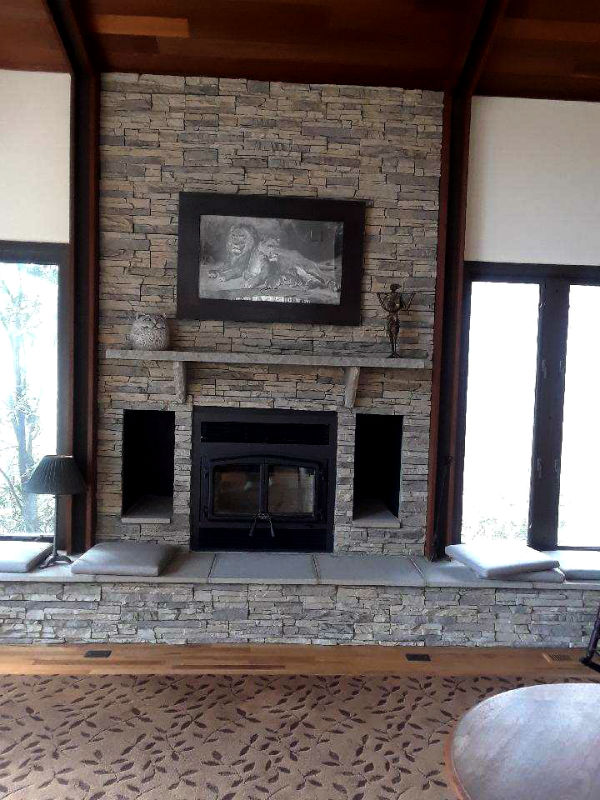 Osburn Hybrid Wood Fireplace Insert with layered stone surround, mantel and hearth. Beautiful picture of Lion and Lioness over mantel - windows on each side of fireplace.