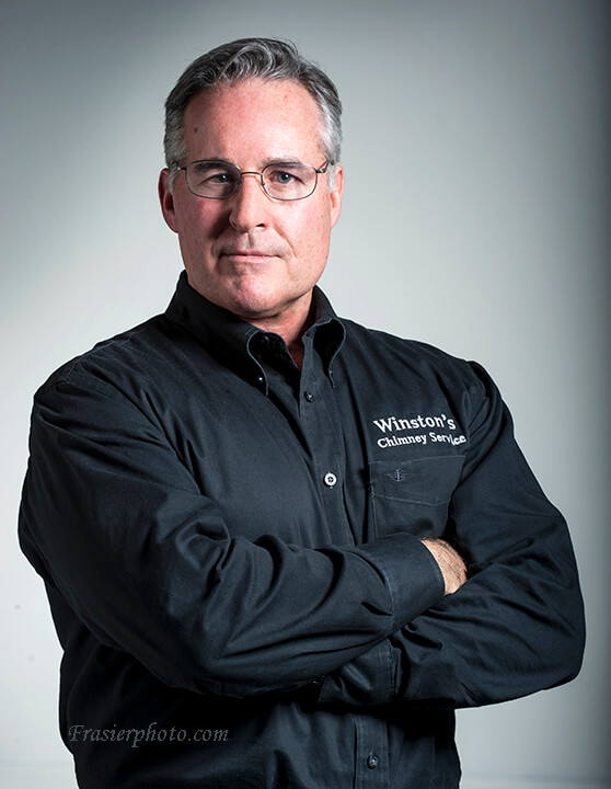 Winstons Chimney Services Owner, Chuck Hall - Arlington and Manassas, VA and Washington, DC Winstons Chimney Services Owner, Chuck Hall with graying short hair, blue eyes, wire framed glasses and a black Winston's button down shirt.