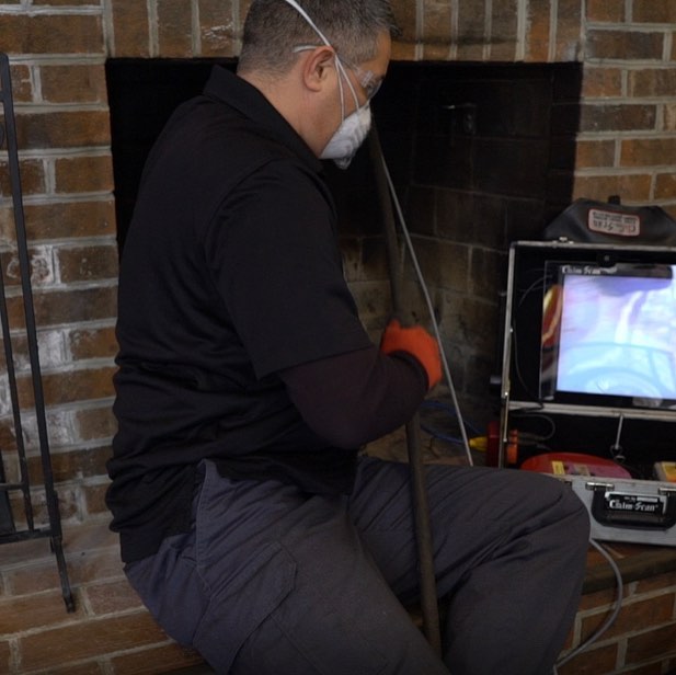 technician looking at a video device to inspect a fireplace