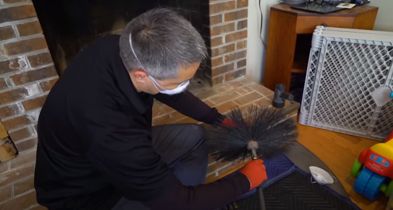 chimney technician with a sweeping brush