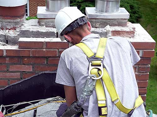 Close up of view of technician completing chimney repairs on a roof