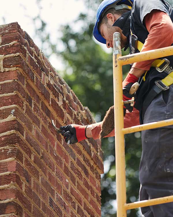Technician standing on scaffolding while repairing chimney masonry