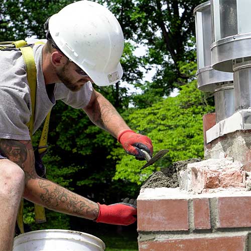 Close up of chimney technician laying mortar for chimney crown repair