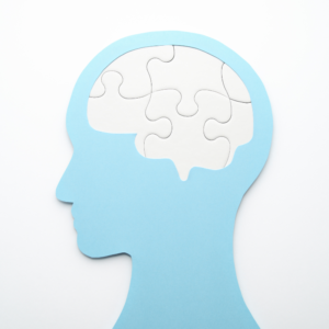 a graphic of a side profile of a blue head with a brain pieced together with puzzle pieces