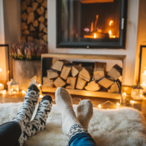 two feet propped up in front of a wood burning fireplace