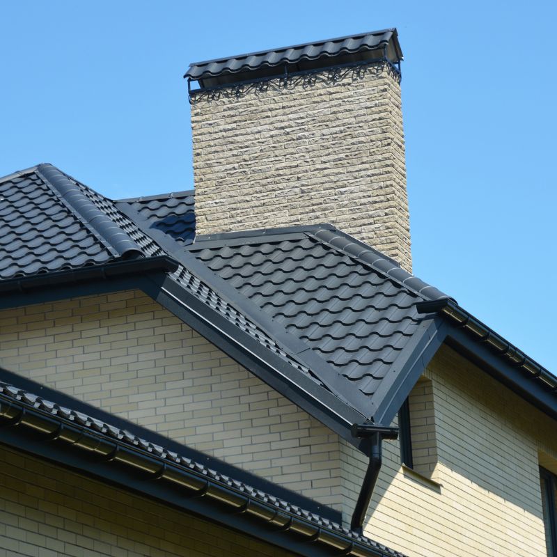 a large stone chimney coming out of a black roof