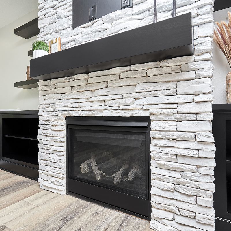 a black gas fireplace with a white stone facing surrounding it