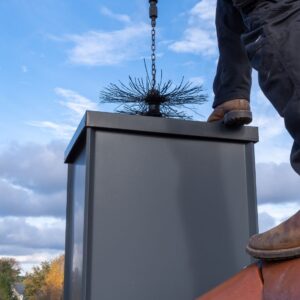 a chimney sweep brush going into a metal chimney from the top