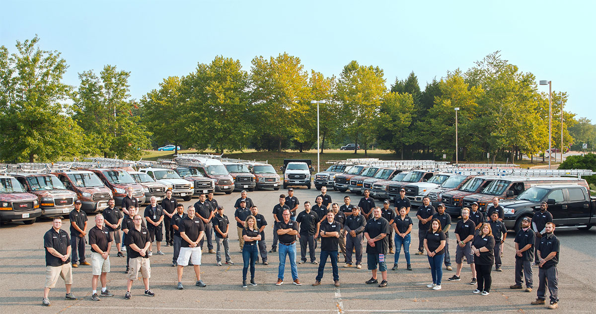 Winstons team photo with work trucks and vans in the background.