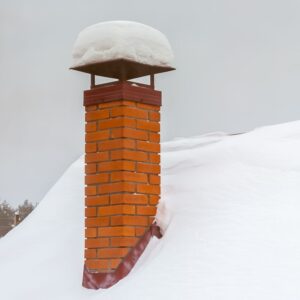 masonry chimney with a chimney cap covered in snow