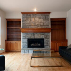 a stone fireplace with a gas insert in a living room with couches and a coffee table