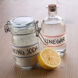 two clear bottles labeled "vinegar" and "baking soda" next to a lemon