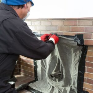 a technician taping a tarp over a chimney opening to prepare for a sweep
