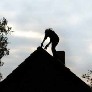 silhouette of a chimney technician inspection a chimney on a roof