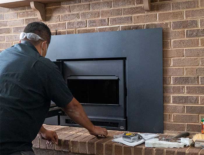 Man-kneeling-in-front-of-newly-installed-fireplace Man-kneeling-in-front-of-newly-installed-fireplace