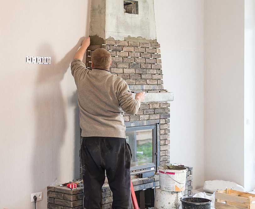 Tech refacing a fireplace.  Fireplaces should never be used during restoration.