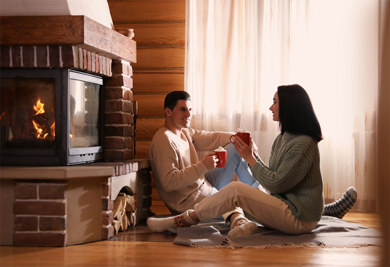Couple drinking hot cocoa in front of a fireplace